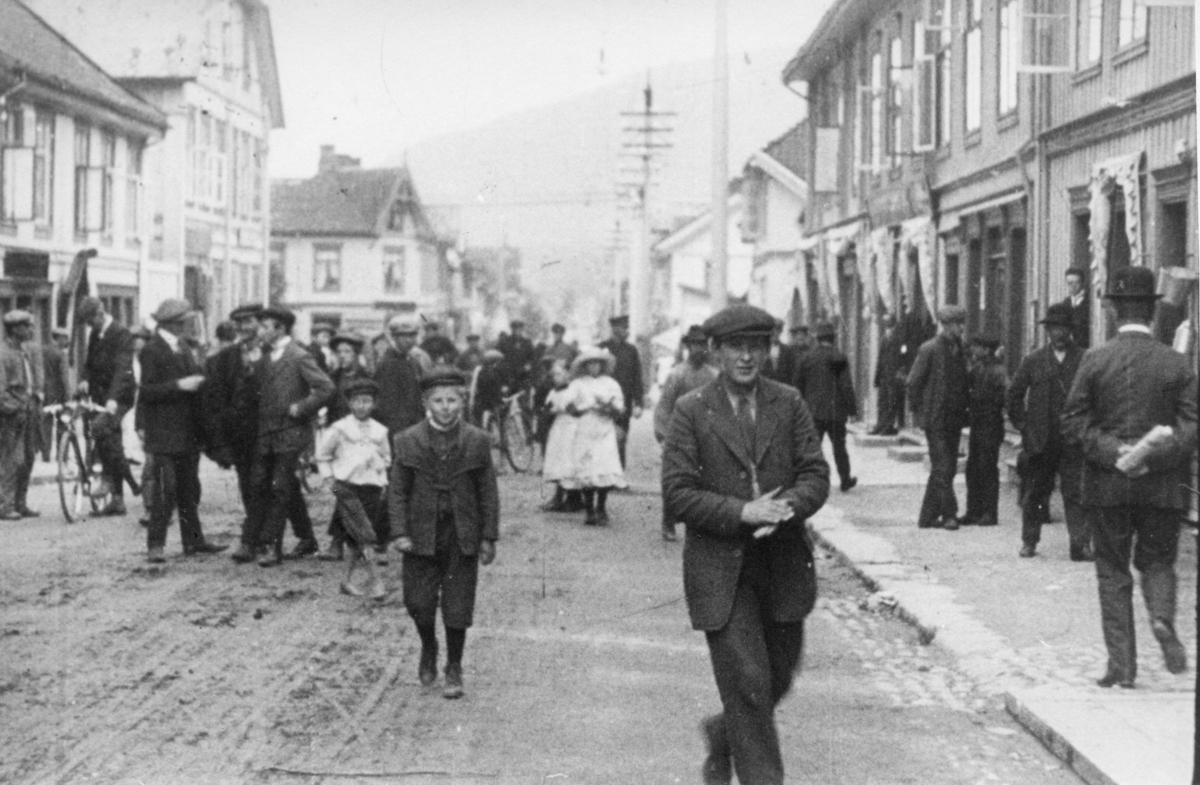 Stillbilde fra Albert Hougners film fra Storgata, Lillehammer 1912. Storgata sør for Mesnabrua med Storgata 82 og 84 Victoria Hotel til venstre og nr. 79 og 81 til høyre. Mange folk i gata.
