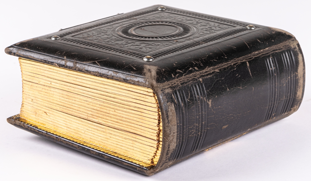 Fotoalbum, i svart papp. Dekor med gyllene ornamentik och plåtmedaljong samt lås. Albumet har tillhört Gustaf Swedlund.