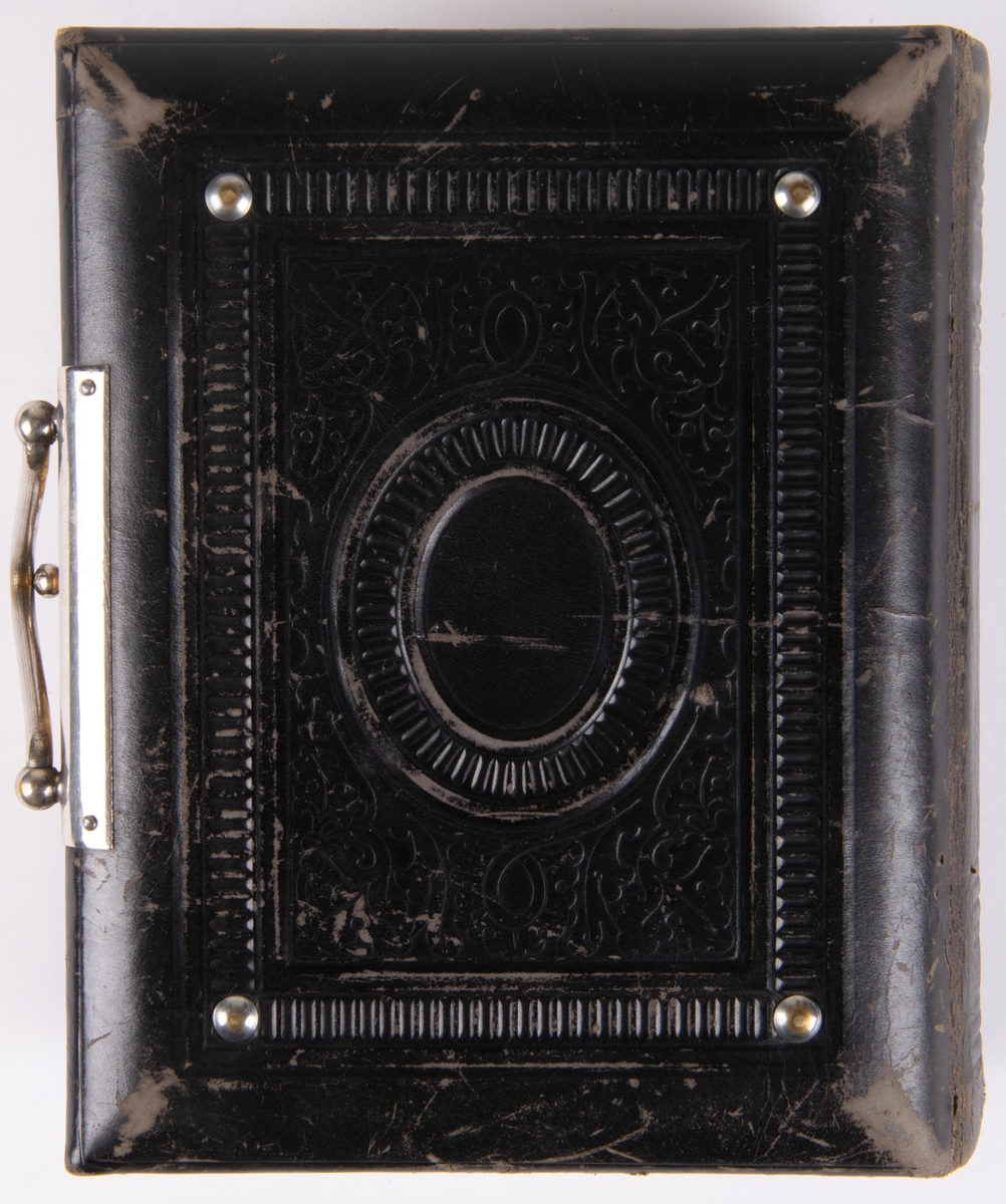 Fotoalbum, i svart papp. Dekor med gyllene ornamentik och plåtmedaljong samt lås. Albumet har tillhört Gustaf Swedlund.