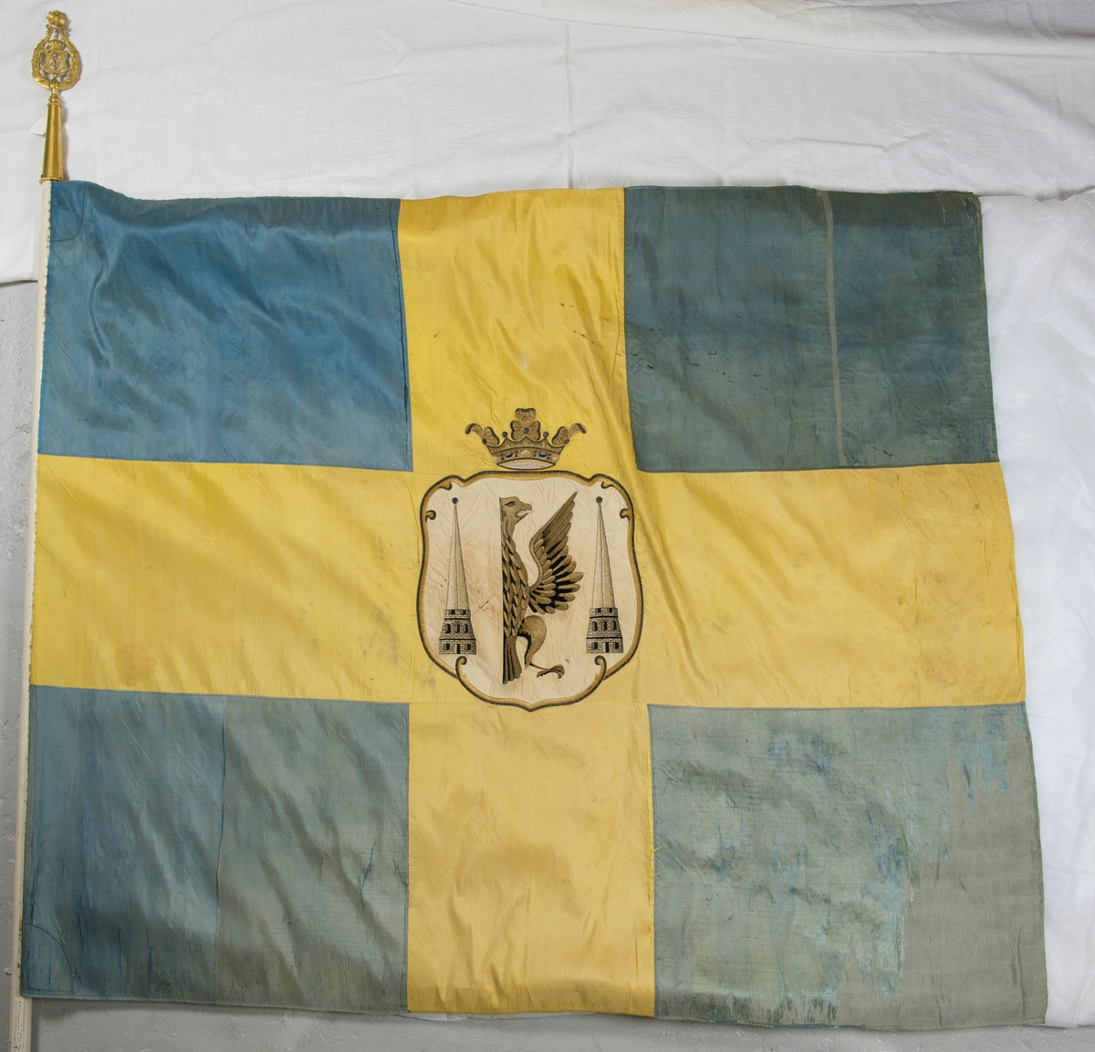 Fana av gult och blått natursiden, dubbet tyg, med heraldiskt motiv: Karlstads stadsvapen. Motivet är placerat i mitten av det gula korset och består av en applikation av vitt siden med heltäckande broderi. Fanan är fäst på vitmålad stång med en fanspets i metall med Carl XV's namnskiffer. Runt skiffret en lyrformad lagerkrans, krönt med symbolen för det allseende ögat med strålar runt.