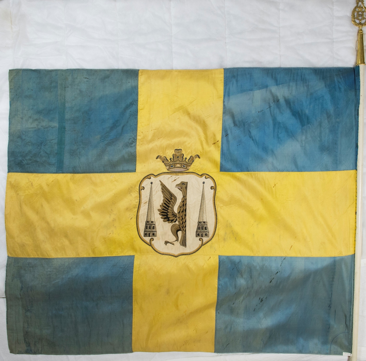 Fana av gult och blått natursiden, dubbet tyg, med heraldiskt motiv: Karlstads stadsvapen. Motivet är placerat i mitten av det gula korset och består av en applikation av vitt siden med heltäckande broderi. Fanan är fäst på vitmålad stång med en fanspets i metall med Carl XV's namnskiffer. Runt skiffret en lyrformad lagerkrans, krönt med symbolen för det allseende ögat med strålar runt.