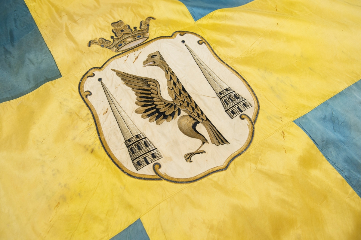 Fana av gult och blått natursiden, dubbet tyg, med heraldiskt motiv: Karlstads stadsvapen. Motivet är placerat i mitten av det gula korset och består av en applikation av vitt siden med heltäckande broderi. Fanan är fäst på vitmålad stång med en fanspets i metall med Carl XV's namnskiffer. Runt skiffret en lyrformad lagerkrans, krönt med symbolen för det allseende ögat med strålar runt.