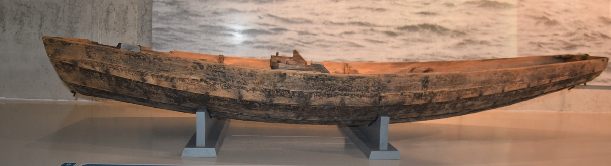 Pram (ferje) med eit par keiper. Jernsaum. To tofter - ei laus og ei fast. Kjetting og tau er festa på innsida framme. Restar av metallband festa i underkant utvendig framme og bak. Prammen er rettskoren framme og bak. Klinkbygd, tre bord.