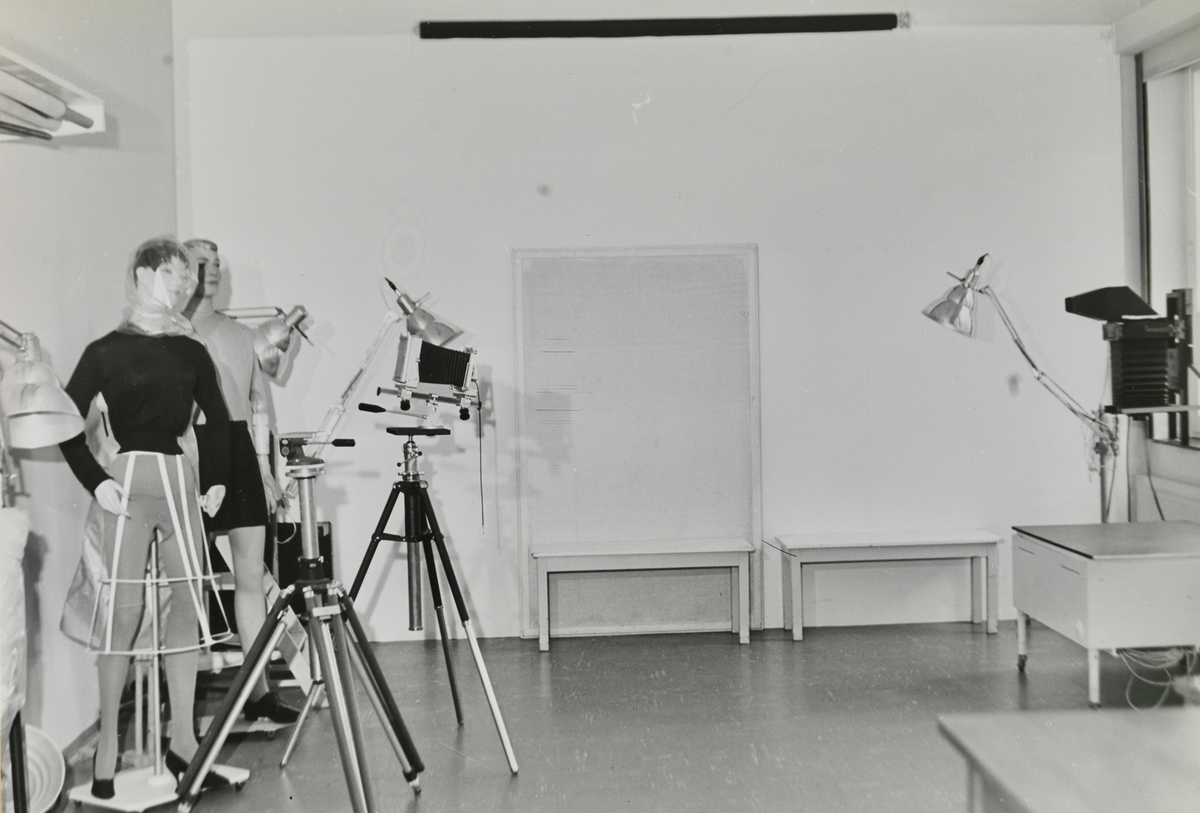 Fotostudio med to modelldukker og fotoutstyr.