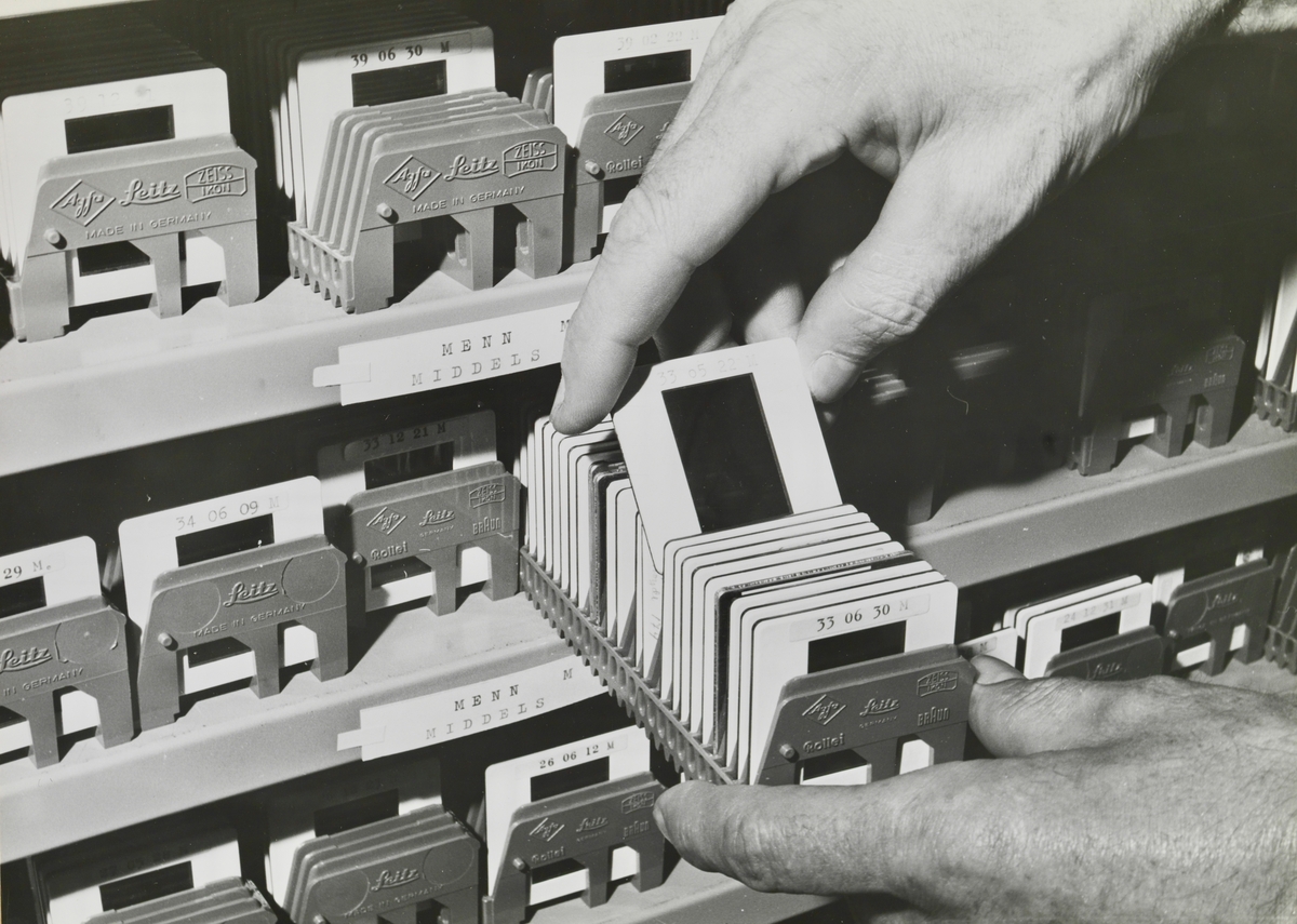 Arkivreoler og nærbilde av hyller med arkiverte lysbilder. Trolig Kriminalpolitisentralens fotoarkiv.