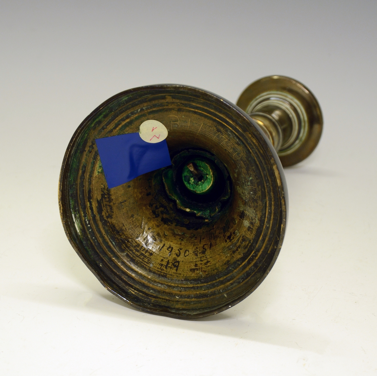 Lysestake av legeringsmetall, "heilrend", med sylinderformet pipe med et par innsnøringer og sirkelformet hov (fot). Pipen er loddet.