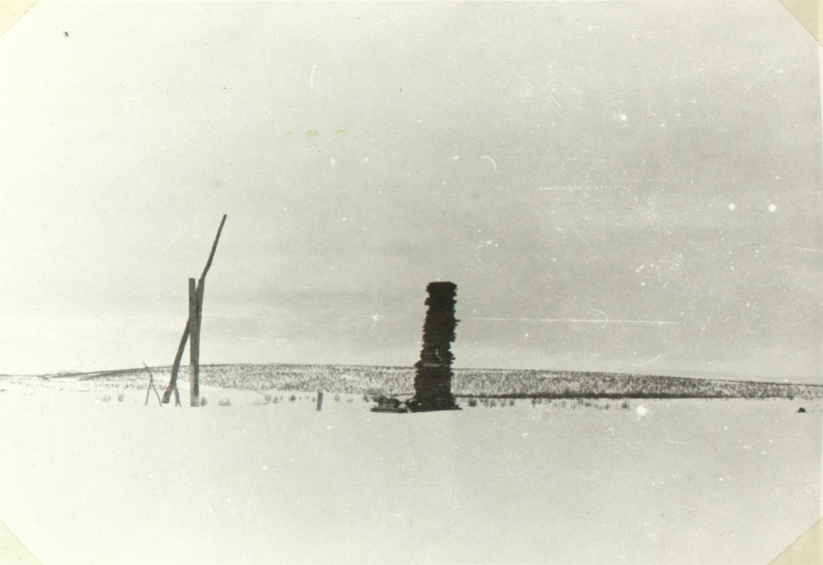 Landskapet er karrig og dekket med snø. I midten av bildet ser man en steinformasjon og en løfteanordning til venstre for det. I tillegg står det en slede ved siden av steinene.
