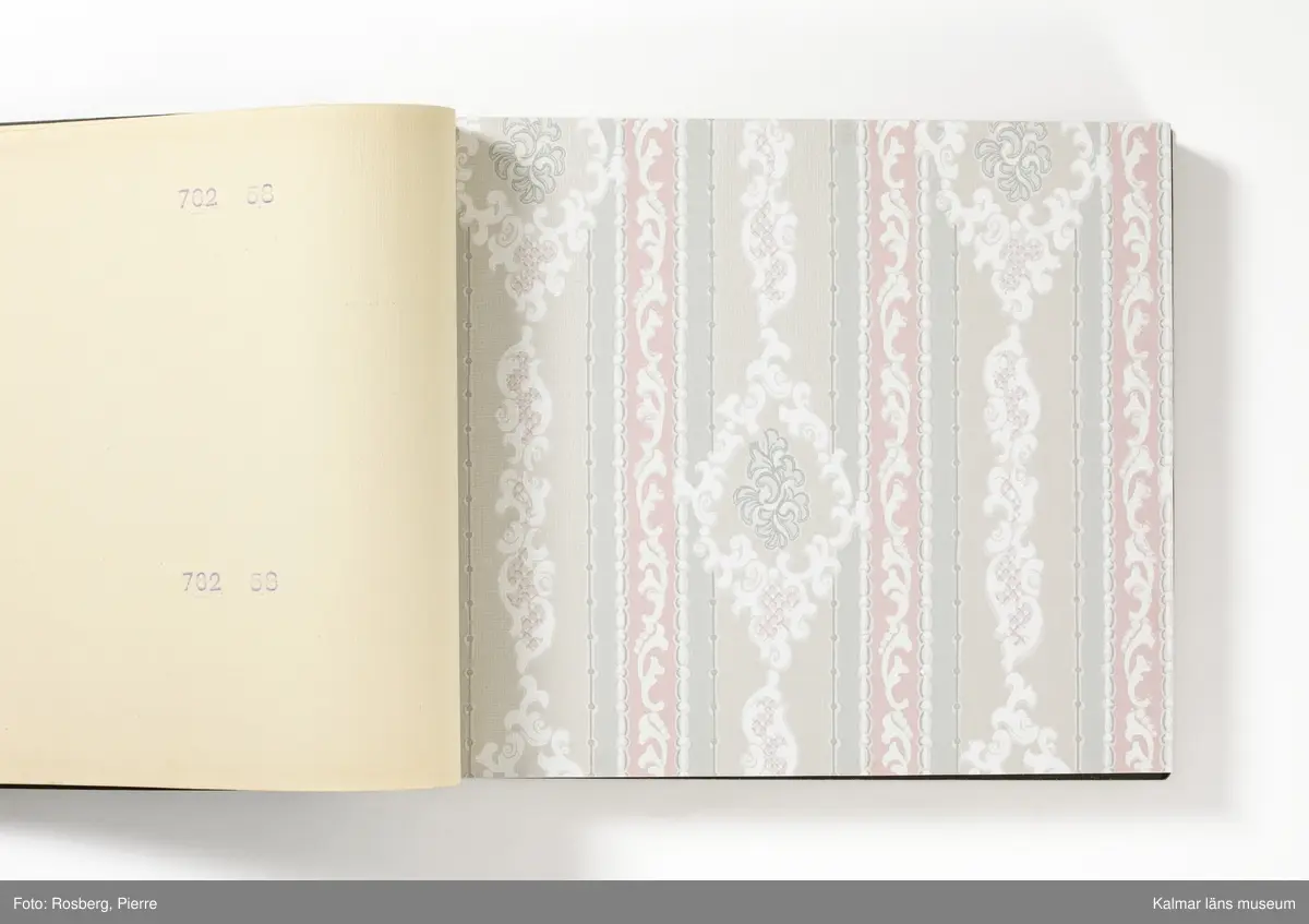 KLM 46599:3. Tapetkatalog. Katalog med pärm av grön papp eller kartong. Bunden med hjälp av tre metallnitar. Text i silver på pärmens framsida: EMMABODA TAPETFABRIK AB Emmaboda. Katalogen innehåller en mängd olika plastförstärkta tapetprover tillverkade av papper, med olika strukturer, färger och mönster, moderna under 1950 och 1960-talen.