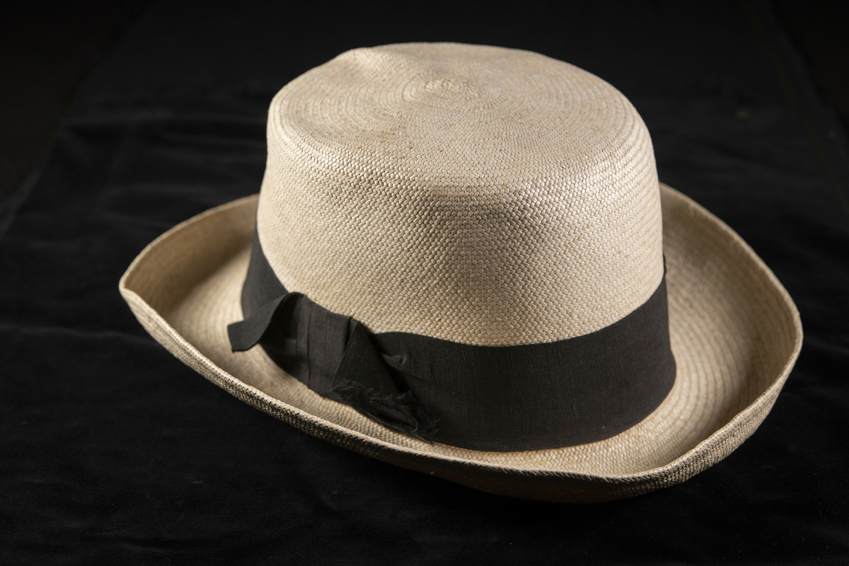 Stråhatt, tätt flätad med rak kulle och rundat, uppvikt brätte. Naturfärgad med svart hattband, svettband i brunt läder.