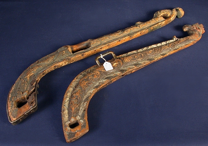 Bogträ med sniderier i barockstil. Krönet utgörs av ett griphuvud med adlig krona. Kroppen består av heltäckande, slingrande bladmotiv. En järnbygel för bröstremmen. Bladmotiven har usprungligen haft en grön färg på en mättad rödbrun bottenfärg.