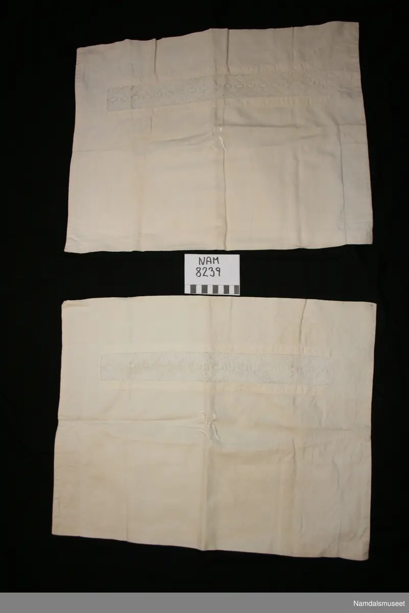 Rektangulært putevar med blonde mellomverk og monogram. Monogrammet er en brodert R