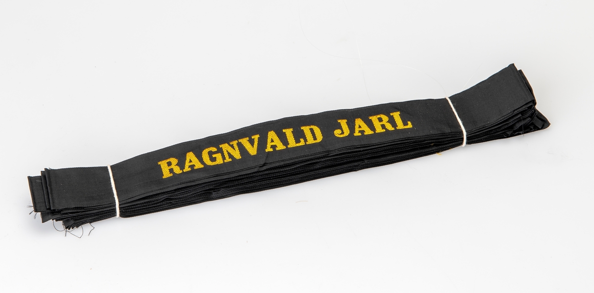 24 i dentiske luebånd til å feste på uniformslue. De er laget av svart kunstsilke. På midten er det maskinbrodert "Ragnvald Jarl" med gullfarget tråd.