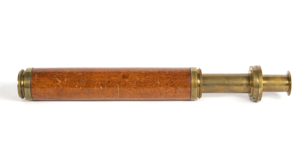 Tub av fernissad mahogny med insatstuber av mässing. Okularet försett med distansskala i alnar.