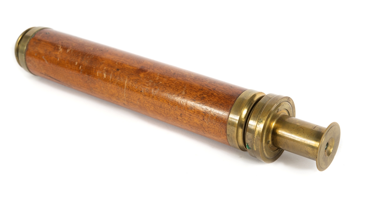 Tub av fernissad mahogny med insatstuber av mässing. Okularet försett med distansskala i alnar.