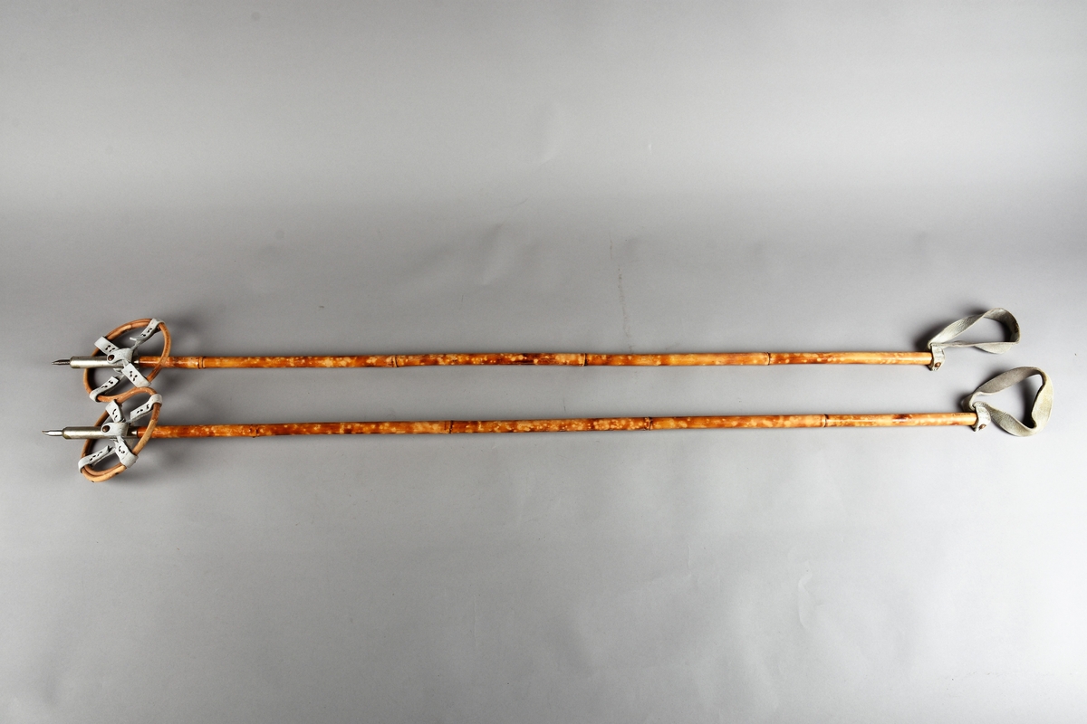 Eit par ski av tre. Kandaharbinding. Eit par skistavar. To reimer til å halde det saman. Ein reisegodslapp heng fast i B.