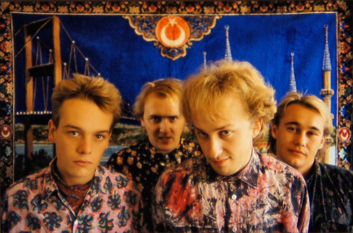 Et bilde av bandet Heart of Mary. Fire unge gutter poserer foran et teppe. De har på mønstrete skjorter.