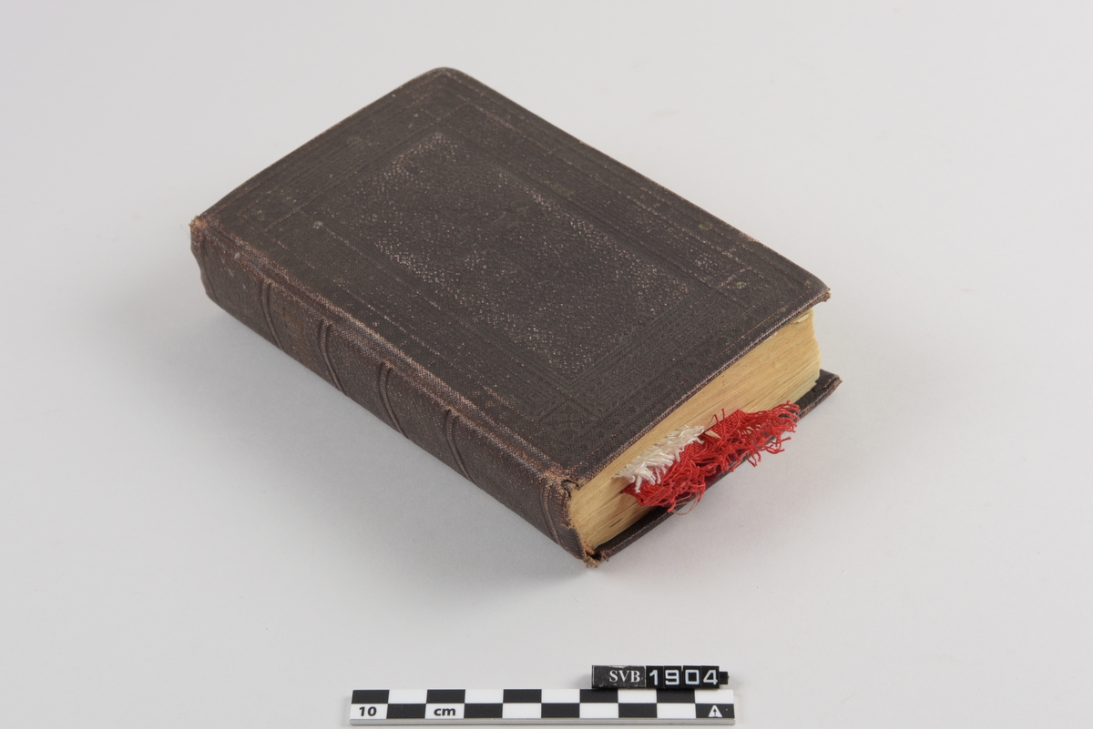 Bibel. Innbundet bok med flere bokmerker laget av forskjellig type tekstil. Et heklet kors og 3 rektangulære tekstilbånd med og uten mønster i forskjellige farger.