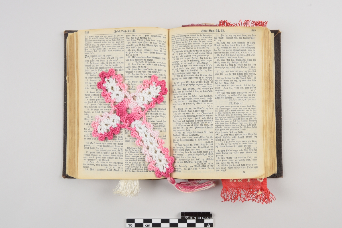 Bibel. Innbundet bok med flere bokmerker laget av forskjellig type tekstil. Et heklet kors og 3 rektangulære tekstilbånd med og uten mønster i forskjellige farger.