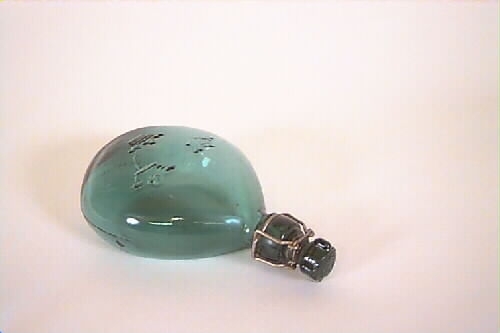 Flaska av grönt glas med mönstrad relief i form av tre kronor på framsidan. Patentkork av glas i metallbygel.