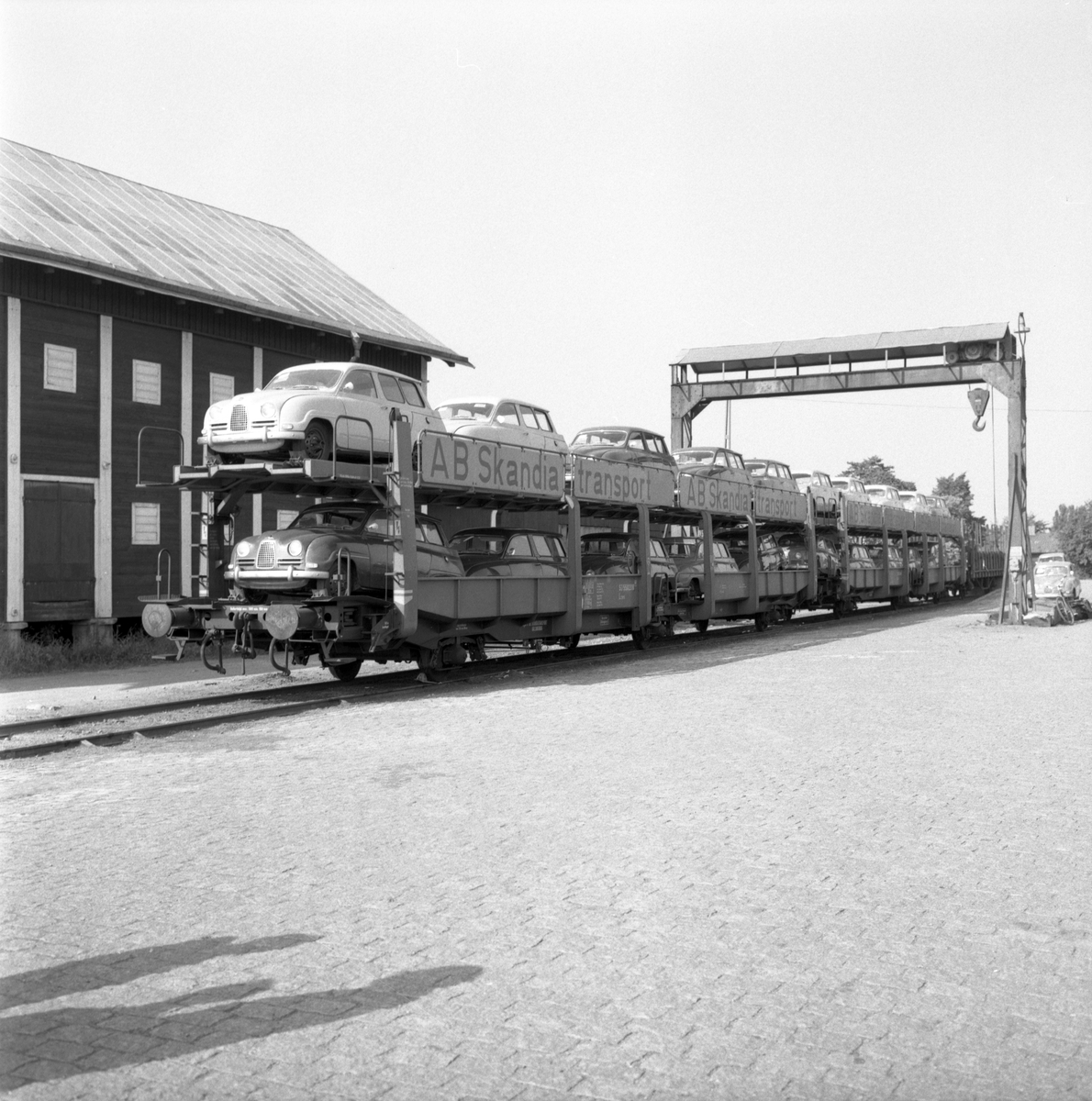 En serie Saabar av modell 95 lastade vid Tannefors station för vidare export till USA. Modellen som lanserades 1959 tillverkades i förstone vid flygplansfabriken i Linköping. För transporten stod bildens beställare, AB Skandiatransport med säte i Helsingborg.