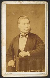 Visittkortfoto, mann fotografert i studio. Mann kledd i dres