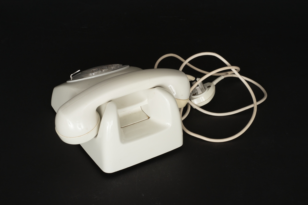 Telefon av gråvit plast med fingerskiva. Lur med spiralformad sladd. Sladd med kontakt. Bottenplatta av metall med inpräglat: Teli MAX MIN och televerksymbol. Siffror under och på nummerskivan.