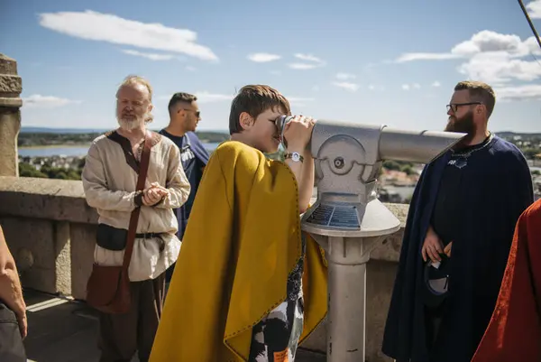 En gutt med gul kappe kikker gjennom en stor kikkert utover Tønsberg fra Slottsfjellstårnet.