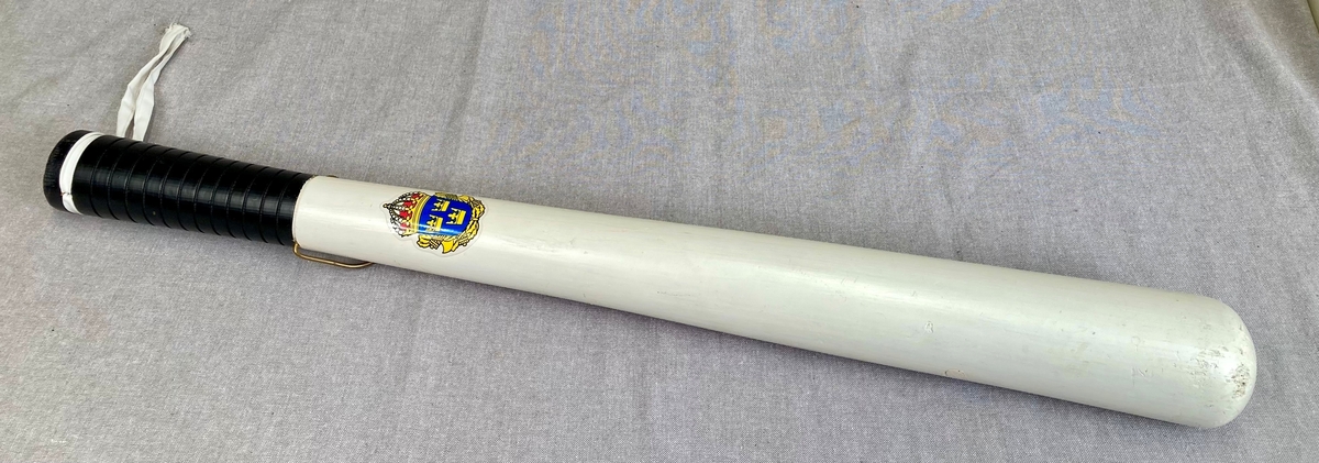 Hvit kølle i tre med bærestropp og svensk politimerking. Svært stor og tung.