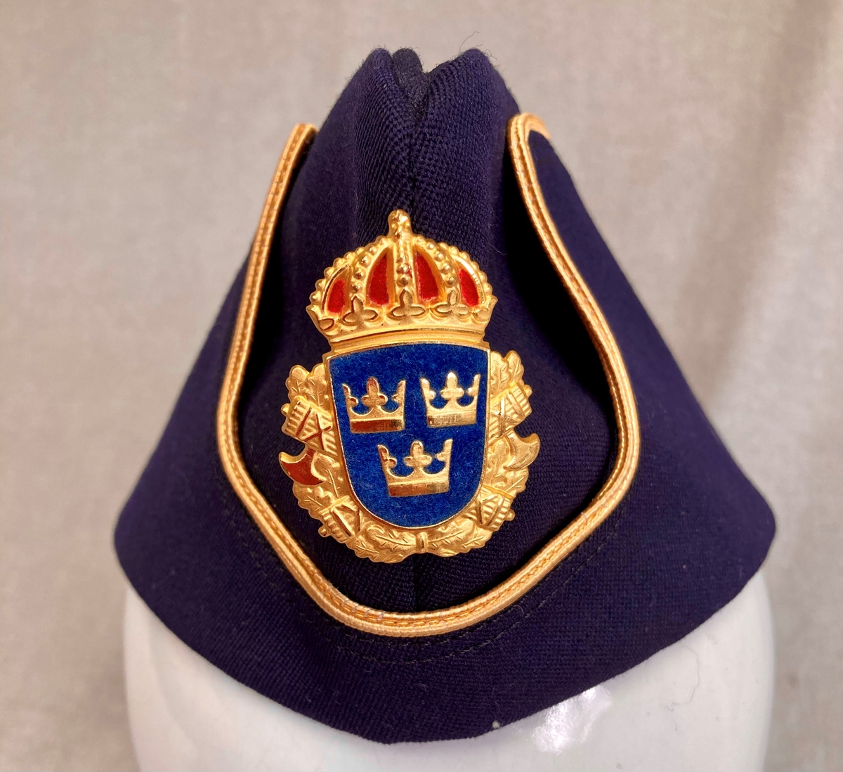 Uniformslue for svensk politi. Mørkeblå båtlue med gulldetaljer og svensk politimerking.