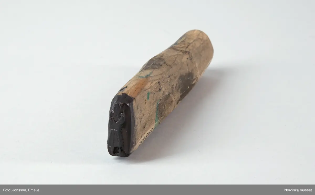 Huvudliggaren:
"Stämpel av björk; utskuren same i ena änden, den andra slät. L ca 13,5 cm, Br ca 3,5 cm. Funnen 15/8 1972 i magasin, ur Johan Turis kvarlåtenskap, anv. vid framst. av bilder ur lapparnas liv; jfr 228.777 - 228.800. G[åva av] Okänd. [Brukningsort:] Lappland Jukkasjärvi sn Talma lappby."