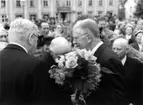 Kung Gustaf VI Adolf med en blomsterbukett hälsar på stadens äldsta innevånare. Till höger skymtar Ivar Ekvall.