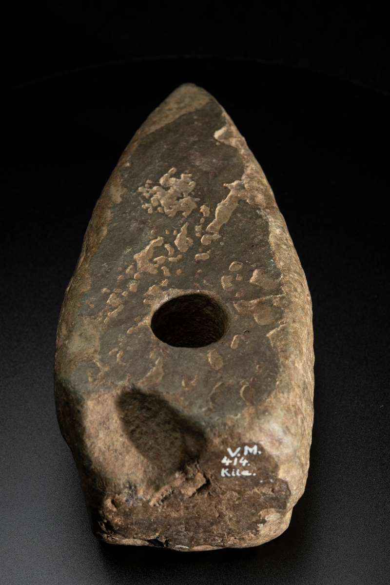 Ett ovanligt stort och klumpigt exemplar. Delvis slipad. Nacken slutar tvärt. Vittrad.