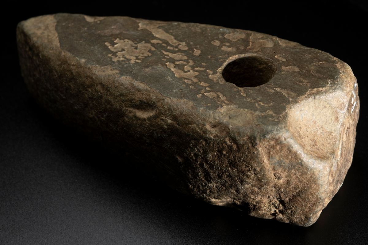 Ett ovanligt stort och klumpigt exemplar. Delvis slipad. Nacken slutar tvärt. Vittrad.