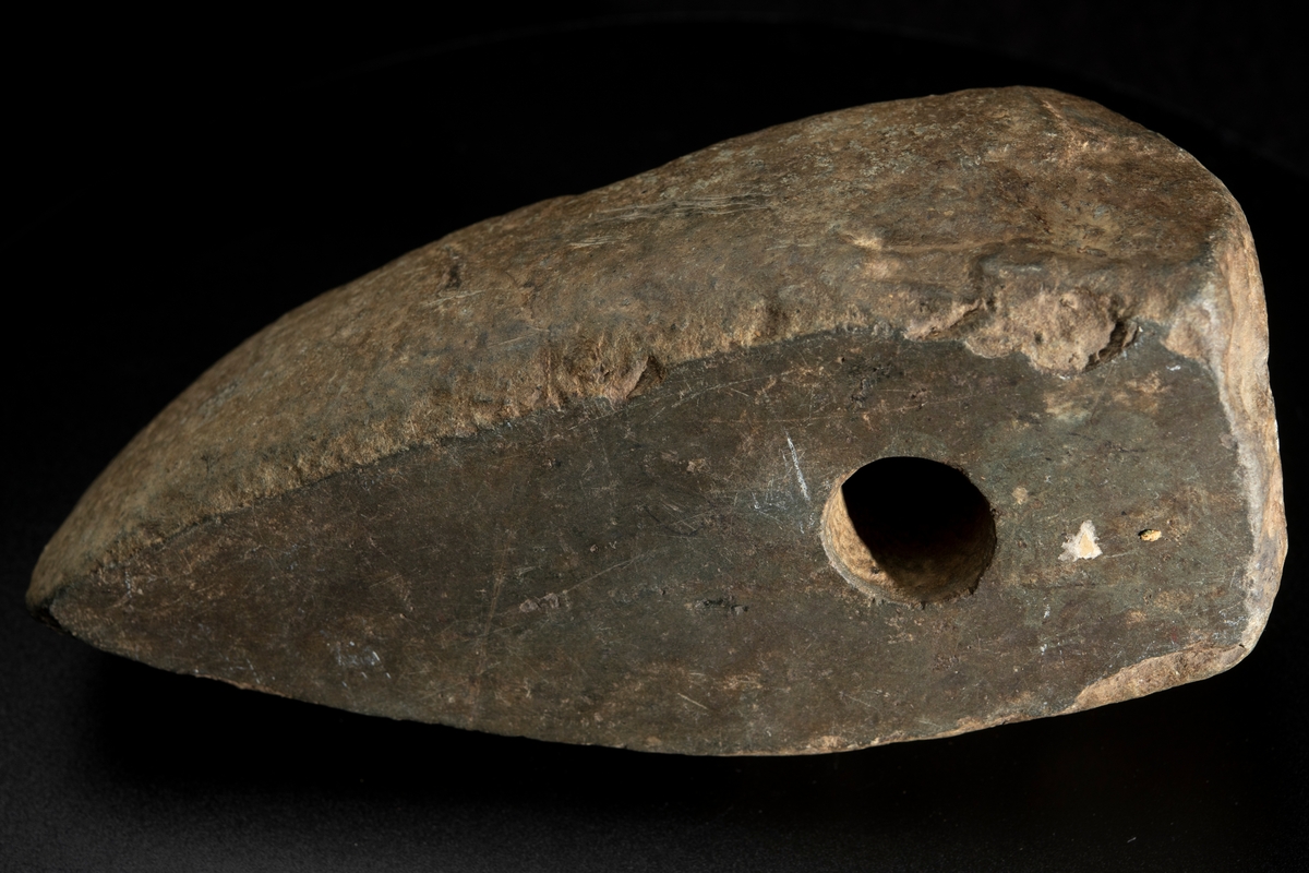 Ett ovanligt stort och klumpigt exemplar. Delvis slipad. Nacken slutar tvärt. Vittrad.