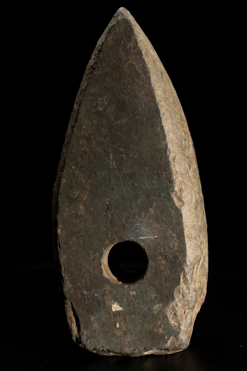 Ett ovanligt stort och klumpigt exemplar. Delvis slipad. Nacken slutar tvärt. Vittrad.