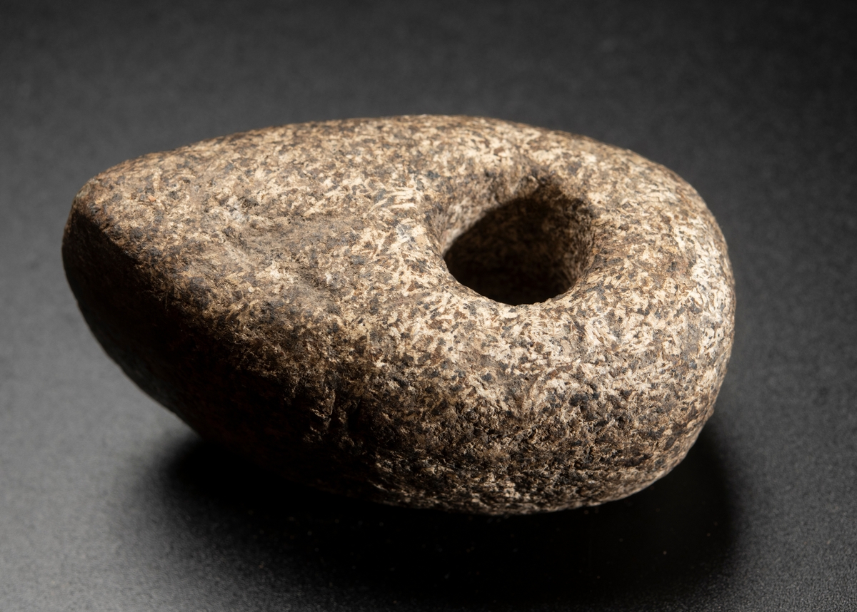 Av grovkornig bergart. Liten och hög. Ovansidan starkt välvd. Nacken slutar tvärt.