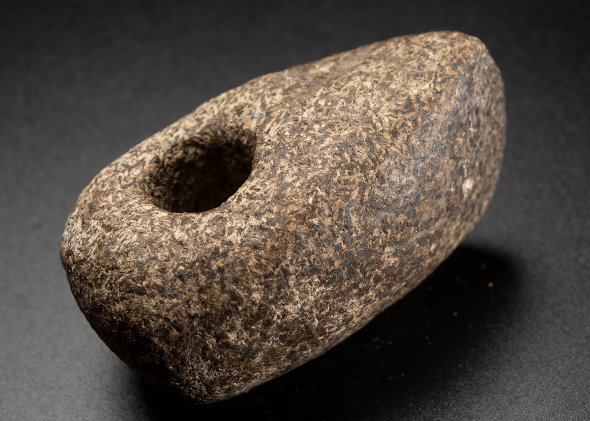 Av grovkornig bergart. Liten och hög. Ovansidan starkt välvd. Nacken slutar tvärt.