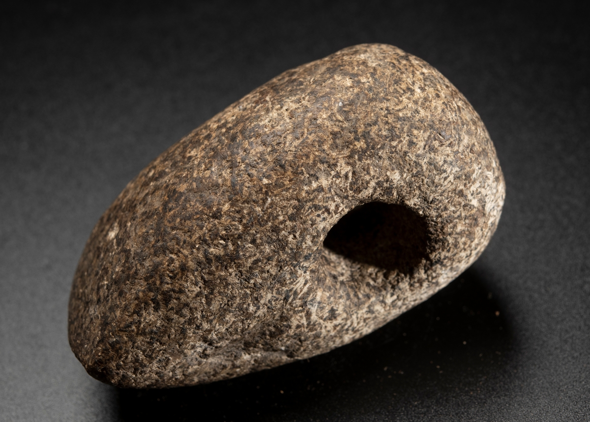 Av grovkornig bergart. Liten och hög. Ovansidan starkt välvd. Nacken slutar tvärt.