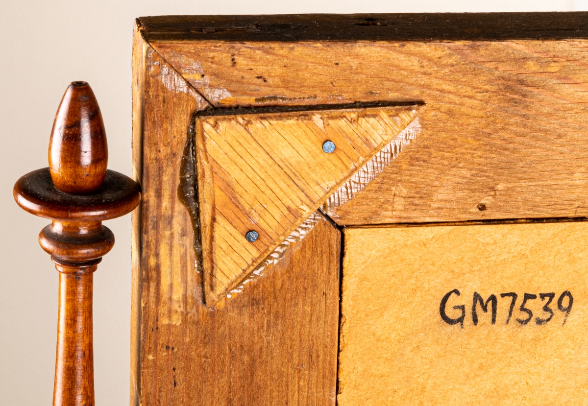 Byråspegel, (lådspegel) av rotmahogny. Med en större och fyra mindre lådor. Svarvade ståndare för spegelns upphängning.