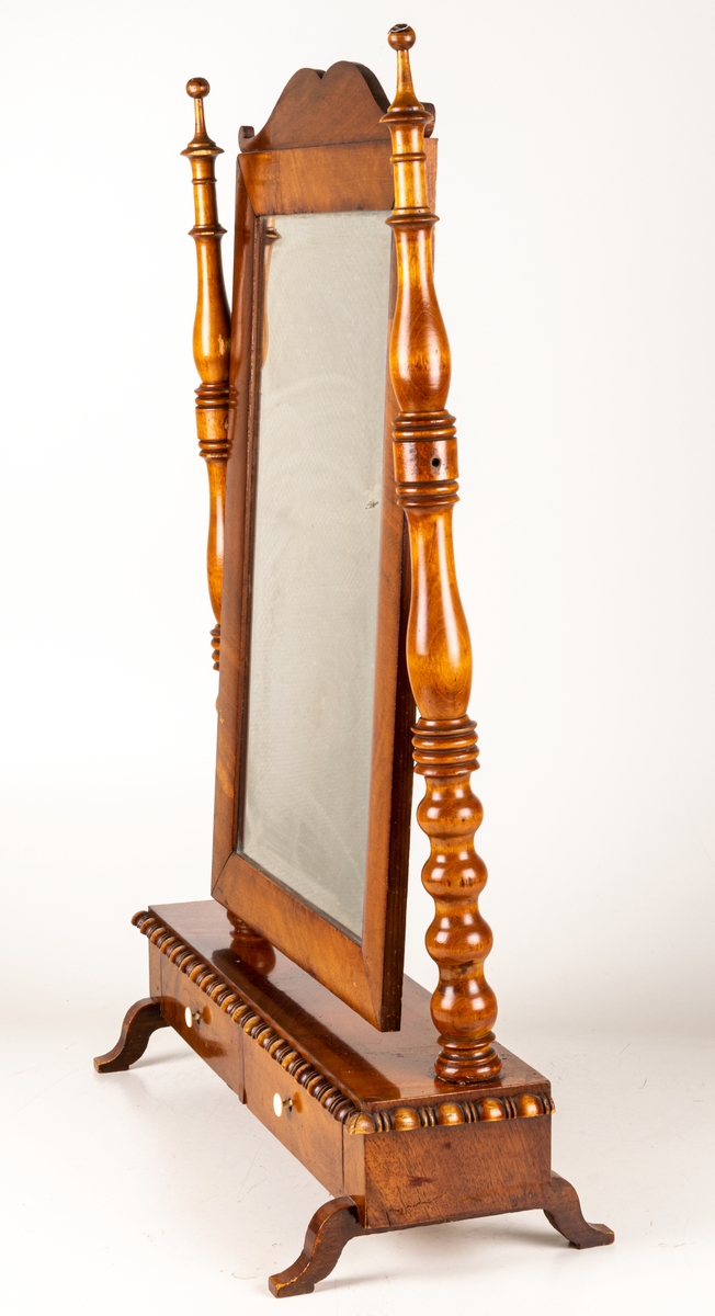 Bordsspegel, brunbetsad. Rektangulär ram med profilerat överstycke. Ramen upphängd på stativ. Två lådor. Svängda fötter. Ostadigt.