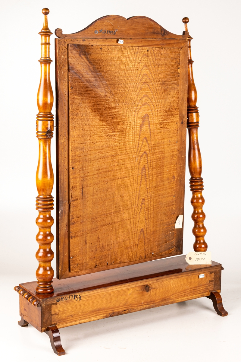 Bordsspegel, brunbetsad. Rektangulär ram med profilerat överstycke. Ramen upphängd på stativ. Två lådor. Svängda fötter. Ostadigt.