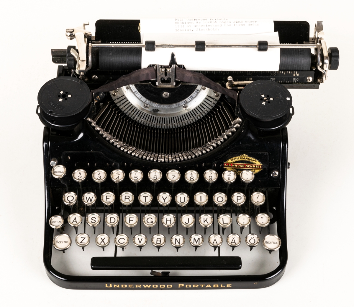 Reseskrivmaskin, Underwood Portable. Svartlackerad plåt. Runda tangenter med text på vit botten under cellulloid och med förnicklade kanter. Text: "UNDERWOOD" resp "UNDERWOOD PORTABLE" i guldfärg samt "A-B HADAR SCHMIDT GENERALAGENT STOCKHOLM". Tillv.nr: 659847.
I svart låsbar låda med bärhandtag. Nyckel saknas.