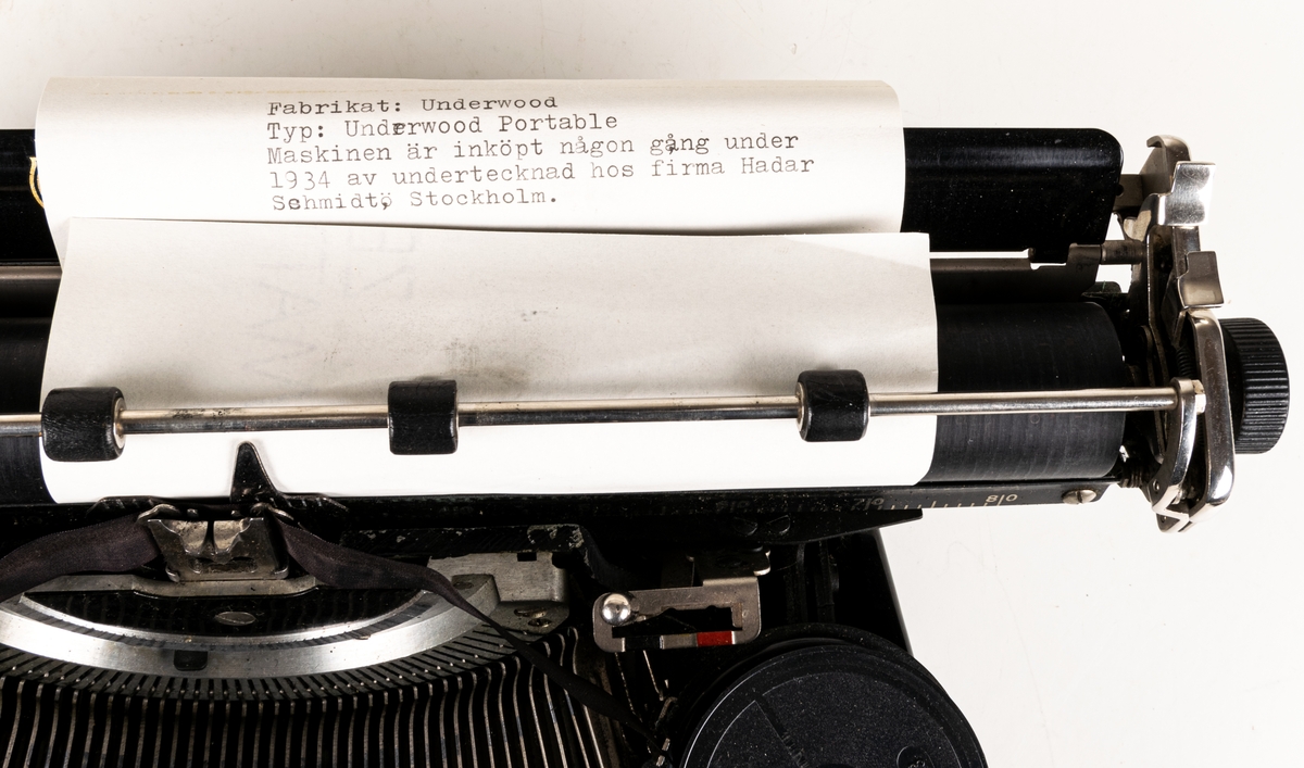 Reseskrivmaskin, Underwood Portable. Svartlackerad plåt. Runda tangenter med text på vit botten under cellulloid och med förnicklade kanter. Text: "UNDERWOOD" resp "UNDERWOOD PORTABLE" i guldfärg samt "A-B HADAR SCHMIDT GENERALAGENT STOCKHOLM". Tillv.nr: 659847.
I svart låsbar låda med bärhandtag. Nyckel saknas.