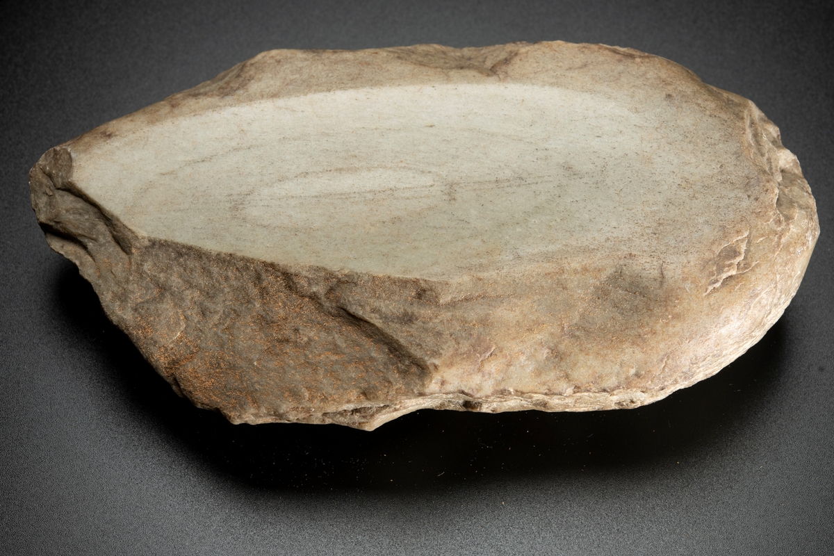 Malsten, av sandsten, oval, platt. Oval även i tvärgenomskärning. Med två konkava slipytor belägna mitt emot varandra på plattsidorna.