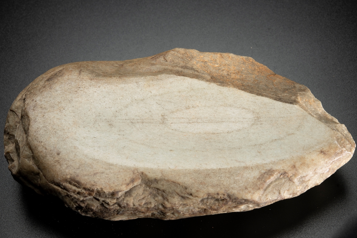 Malsten, av sandsten, oval, platt. Oval även i tvärgenomskärning. Med två konkava slipytor belägna mitt emot varandra på plattsidorna.