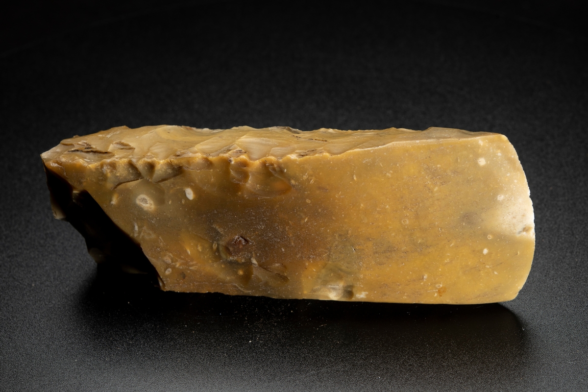 I det närmaste jämnbred. Slipade bredsidor. Avslagen i nacken.