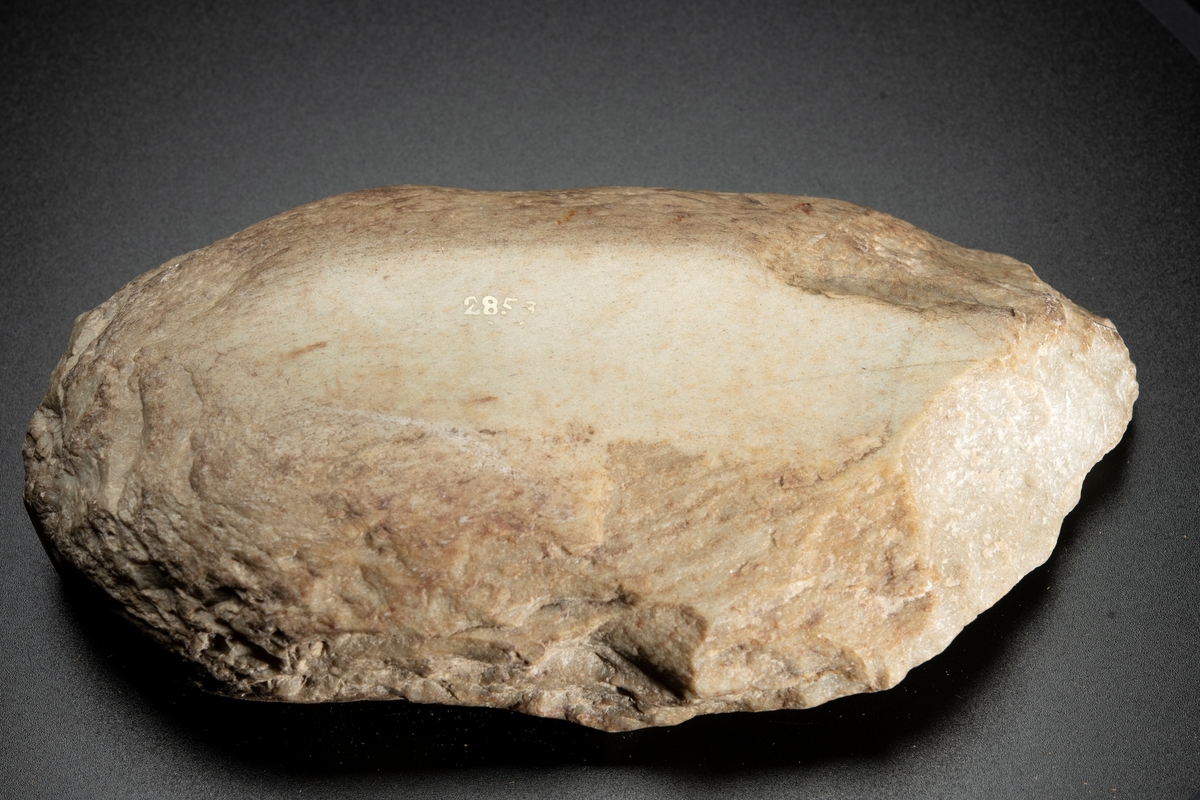 Malsten, av sandsten, oval, platt. Oval även i tvärgenomskärning. Med två konkava slipytor belägna mitt emot varandra på plattsidorna.