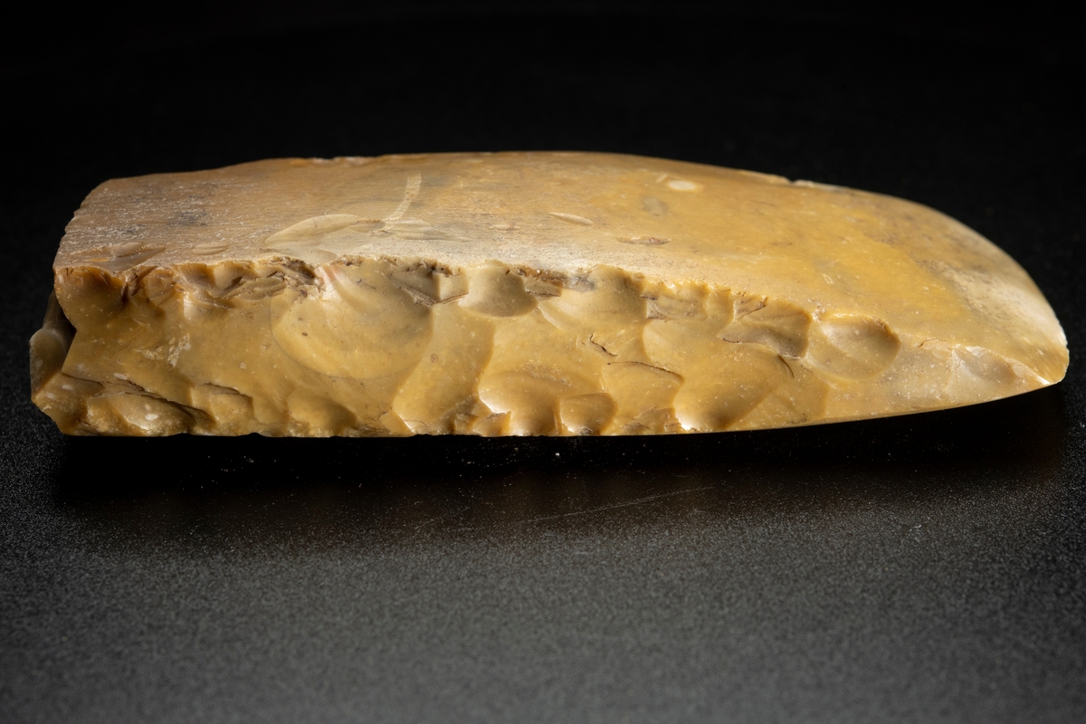 I det närmaste jämnbred. Slipade bredsidor. Avslagen i nacken.