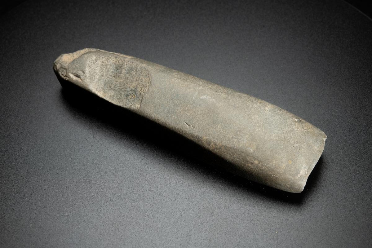 I det närmaste jämnbred. Fyrsidig. Kraftig hålslipning. Helt slipad. Av finkornig bergart.