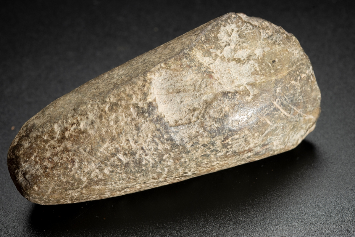 Baneparti av större yxa. Omslagen och omslipad för eggbildning. Starkt välvda bredsidor. Rund i nacken.